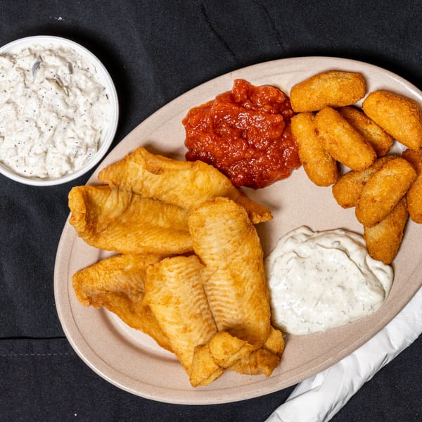 A plate of fried fish, hush puppies, red sauce, and tartar sauce, with a side of coleslaw.