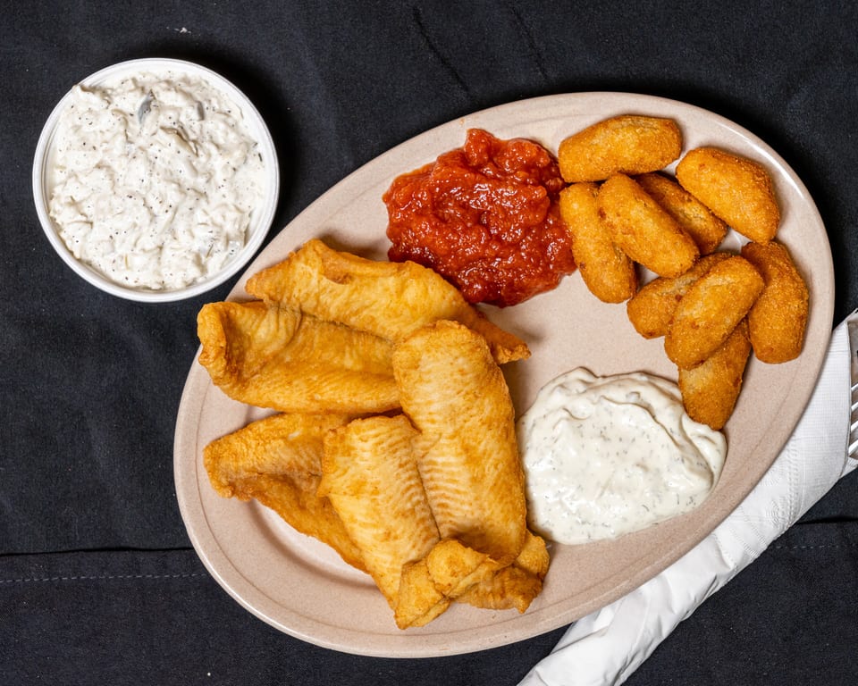 A plate of fried fish, hush puppies, red sauce, and tartar sauce, with a side of coleslaw.